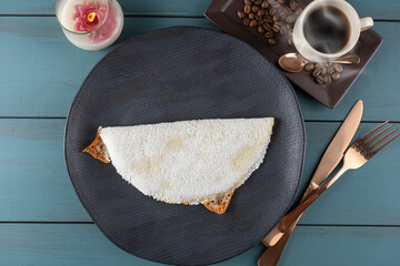 Melted mozzarella cheese tapioca, next to a cup of black coffee_blue wood background. Traditional Brazilian food_9.