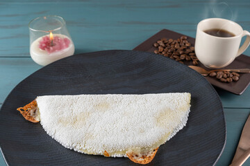 Melted mozzarella cheese tapioca, next to a cup of black coffee_blue wood background. Traditional...