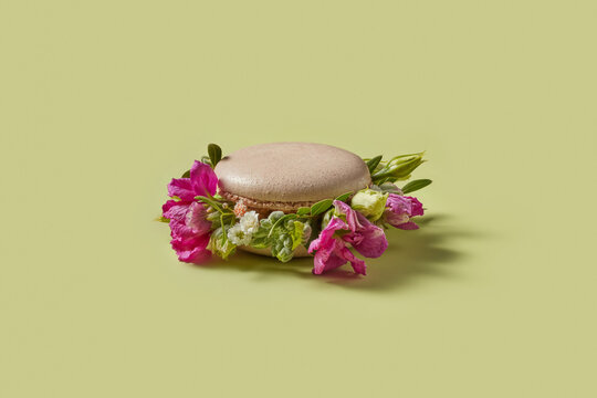 Delicious pink macaron decorated with fresh colorful flowers