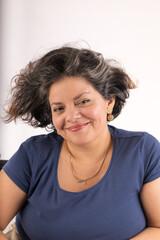 A woman with a blue shirt and a necklace is smiling