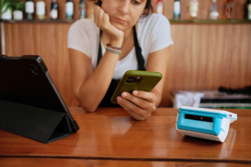 Bored Cashier at a restaurant on her phone