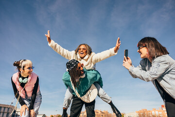 Joyful friends having fun outdoors under blue sky