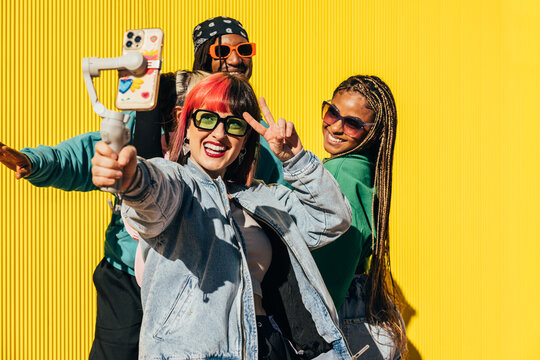 Vibrant friends taking a selfie against yellow background