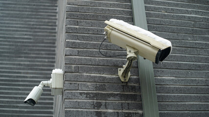 Two surveillance cameras on the exterior wall of a brick building