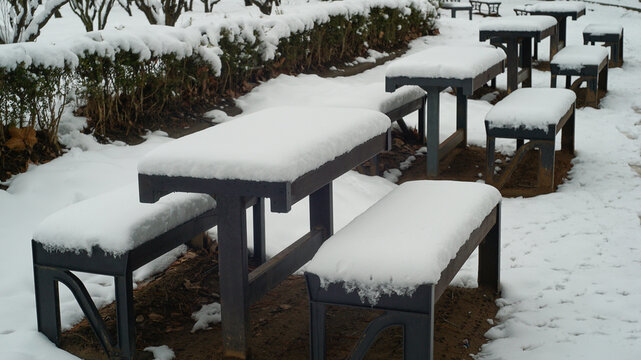 Tables and benches covered in snow in an outdoor park