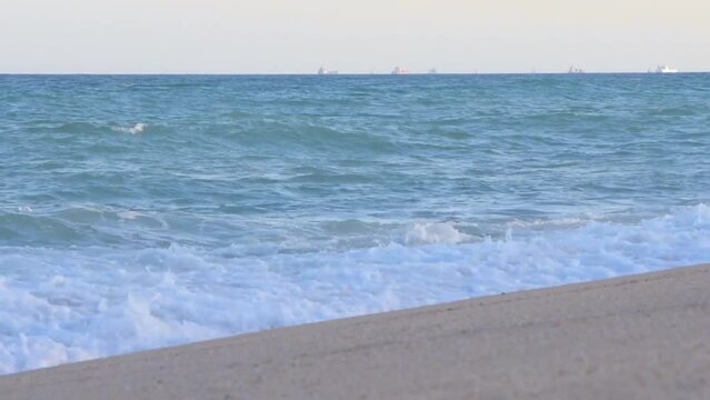 Turquoise sea waves crashing against the sandy coa