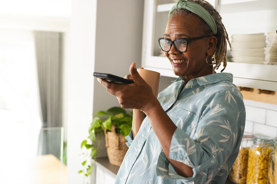 A senior African American woman is holding a smartphone at home, copy space