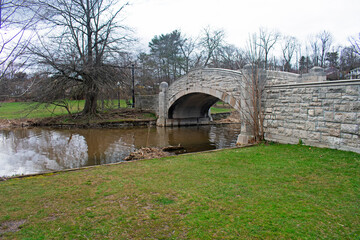Cute stone bridge over Verona Lake in Verona Park, Verona, New Jersey, on an overcast day in early...
