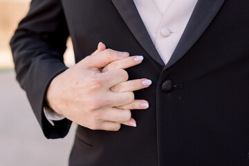 A close-up of a bride and groom's hands as they are holding hands. 