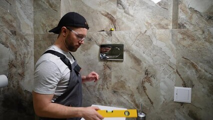 Plumber installing toilet tank in restroom
