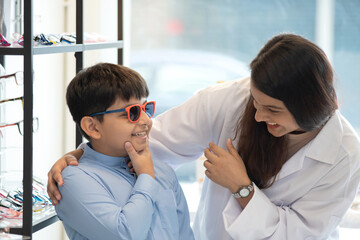 Indian child boy in traditional cloth trying out new eyeglasses with expert advice, Asian boy...