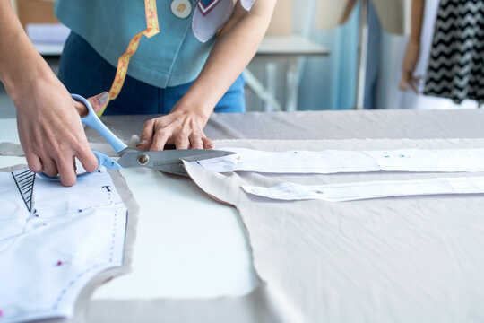Close up, hand of dressmaker or fashion designer working in her workshop, use fabric scissors for the new clothing collection