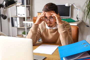 Stressed young man working under deadline in office