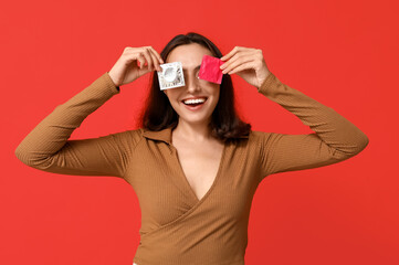 Funny young woman with condoms on red background. Safe sex concept