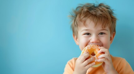 Cute little boy eating a donut - obrazy, fototapety, plakaty