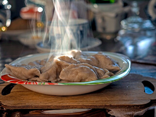 a plate of mouth-watering hot dumplings, steam rises above the plate - 789807255