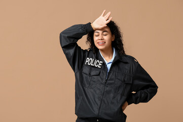 Beautiful young tired African-American policewoman on brown background