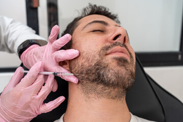 Obraz premium Doctor applying Botox for jawline contouring: cosmetic treatment for male patient's facial definition and skincare, Enhancing jaw with botulinum toxin