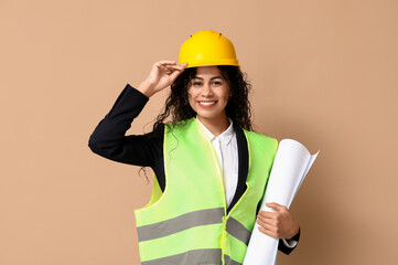 Beautiful young happy African-American female engineer with blueprint on brown background