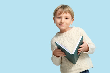 Fototapeta premium Little boy reading book on blue background