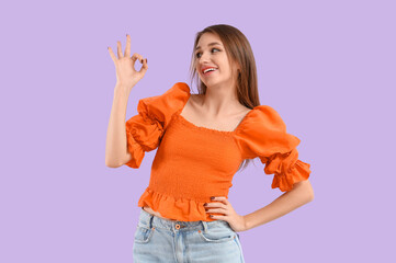Young woman showing OK on lilac background
