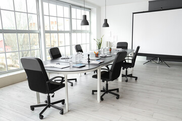 Interior of office with table and projector screen prepared for meeting