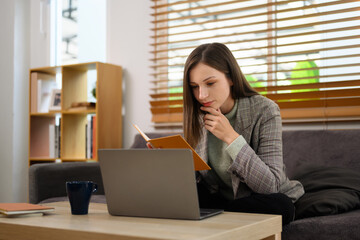 Obraz premium Beautiful caucasian woman looking at laptop screen working remotely at home