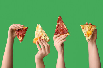 Many hands holding tasty pizza slices on green background