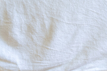 Wrinkled or crumpled white towel texture or background taken with soft natural light used for clothing background or texture