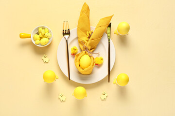 Beautiful table setting for Easter celebration with painted eggs on yellow background. Top view