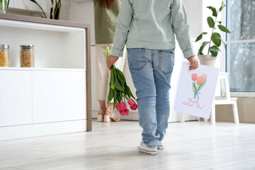 Little girl with bouquet of tulips and drawing going to greeting her mom with Mothers Day in room