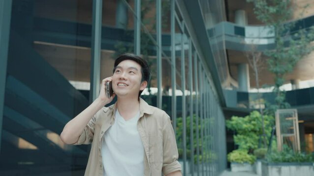 Handsome Asian student using smartphone. A young man walking outdoor happy smiling with talking with mobile phone