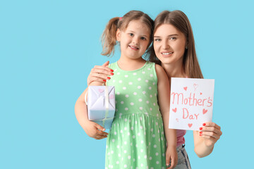 Little girl greeting her mom with Mothers Day with greeting card on blue background