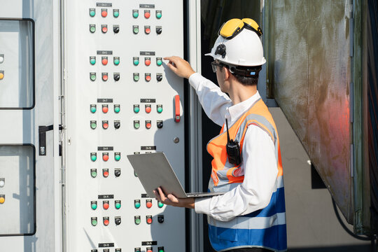 Portrait Asia male engineer in protective workwear is checking a electrical control cabinet or circuit electric control button at rooftop building	