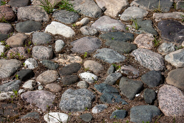 Fragment of a road made of granite stones. Paving stones on the sidewalk. Paving stones made of granite stones on an old road.