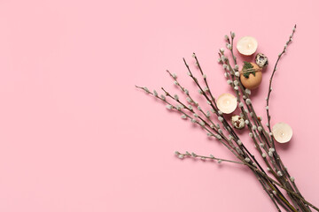 Pussy willow branches with Easter eggs and burning candles on pink background