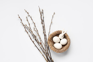Pussy willow branches and nest with Easter eggs on white background