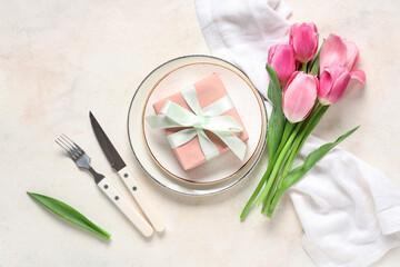 Table setting with greeting card for Mother's day and tulips on white background