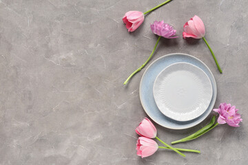 Table setting with tulips on grey grunge background. Mother's day concept