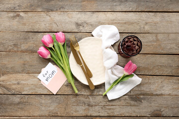 Table setting with greeting card for Mother's day and tulips on wooden background