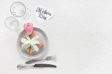 Table setting with greeting card for Mother's day, gift box and tulip on white background
