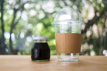 Cold coffee bottle and empty glass on the wooden table. Relaxing with iced coffee at home.