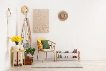 Stylish interior of modern hall with daffodil flowers, hanger and chair