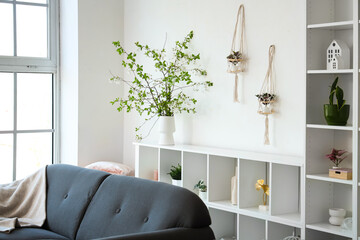 Interior with sofa shelving unit and blooming branches
