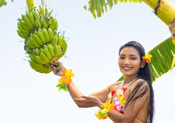 Hawaiian hula dancer offers a bunch of bananas growing on a palm tree
