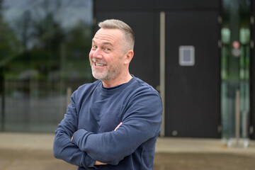 Portrait of a middle aged man looking friendly with a beaming smile to camera with his arms folded