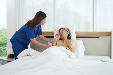 Young Caregiver female take senior woman go to sleep on bed in bedroom