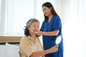 Obraz premium Young Caregiver Tenderly Combing Elderly Woman's Hair