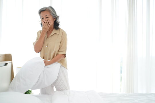 Asian elderly woman was cleaning the dusty bed in bedroom