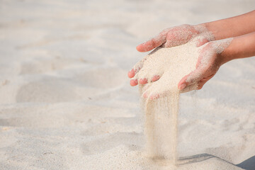 The woman's hand had a certain amount of sand, sand flowing from the woman's hand. desert background